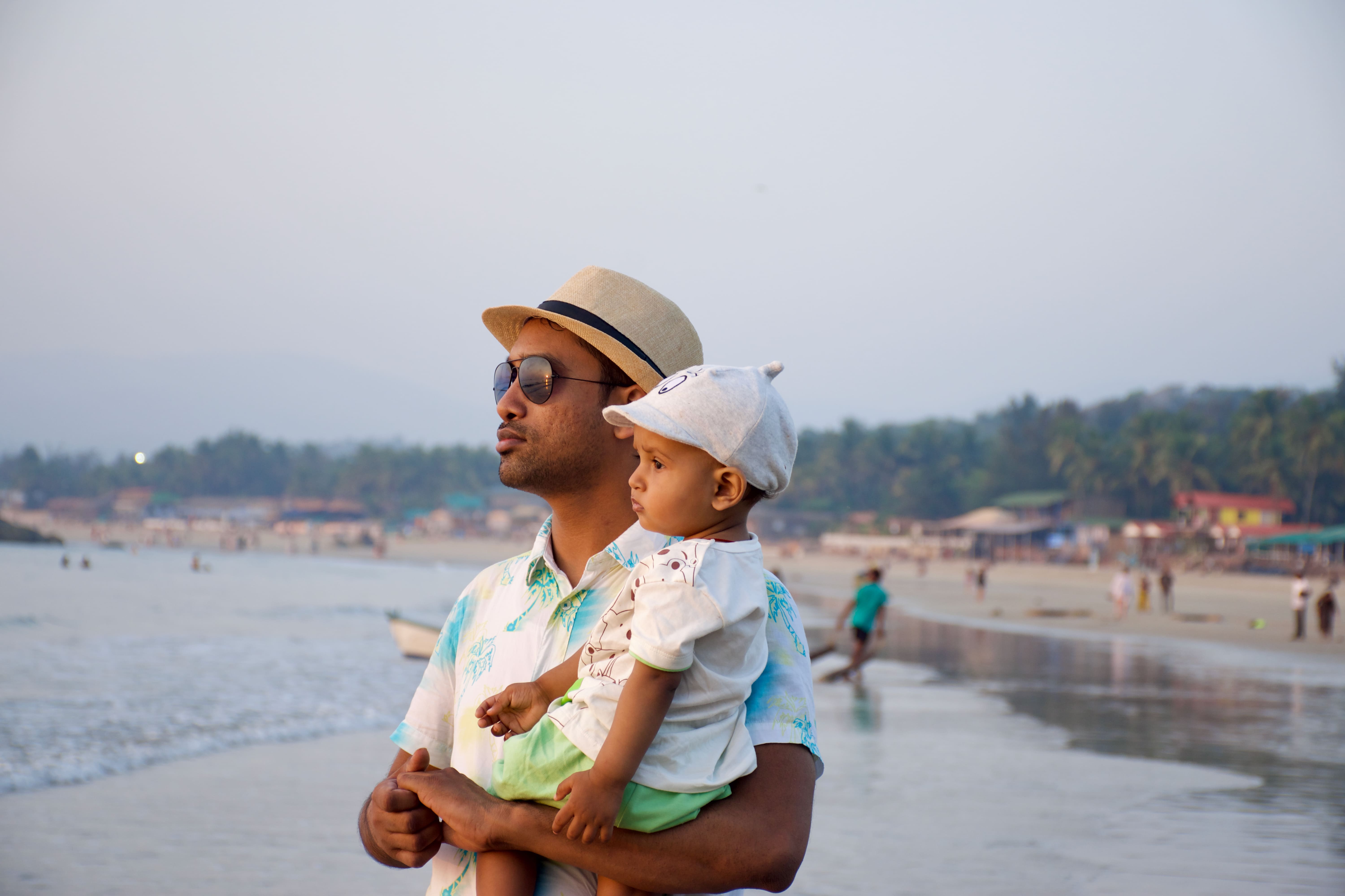 Ravi holding his child on a beach in Goa